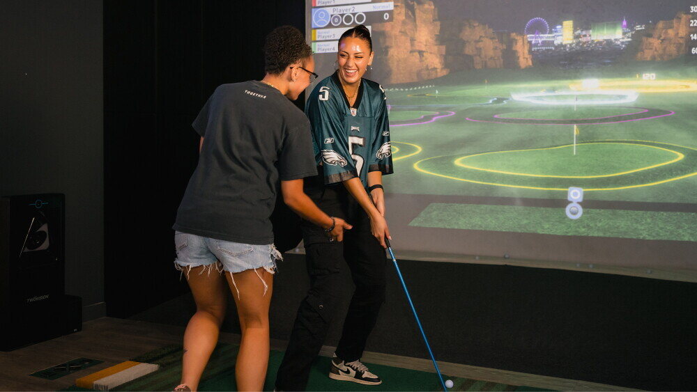 Mixed-age group playing GOLFZON Arcade Plus at Night Glow Range